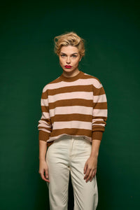 Woman wearing a brown and white striped sweater against a green background