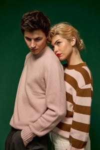 Man wearing a light pink cashmere crew neck sweater with a female wearing a striped cashmere sweater