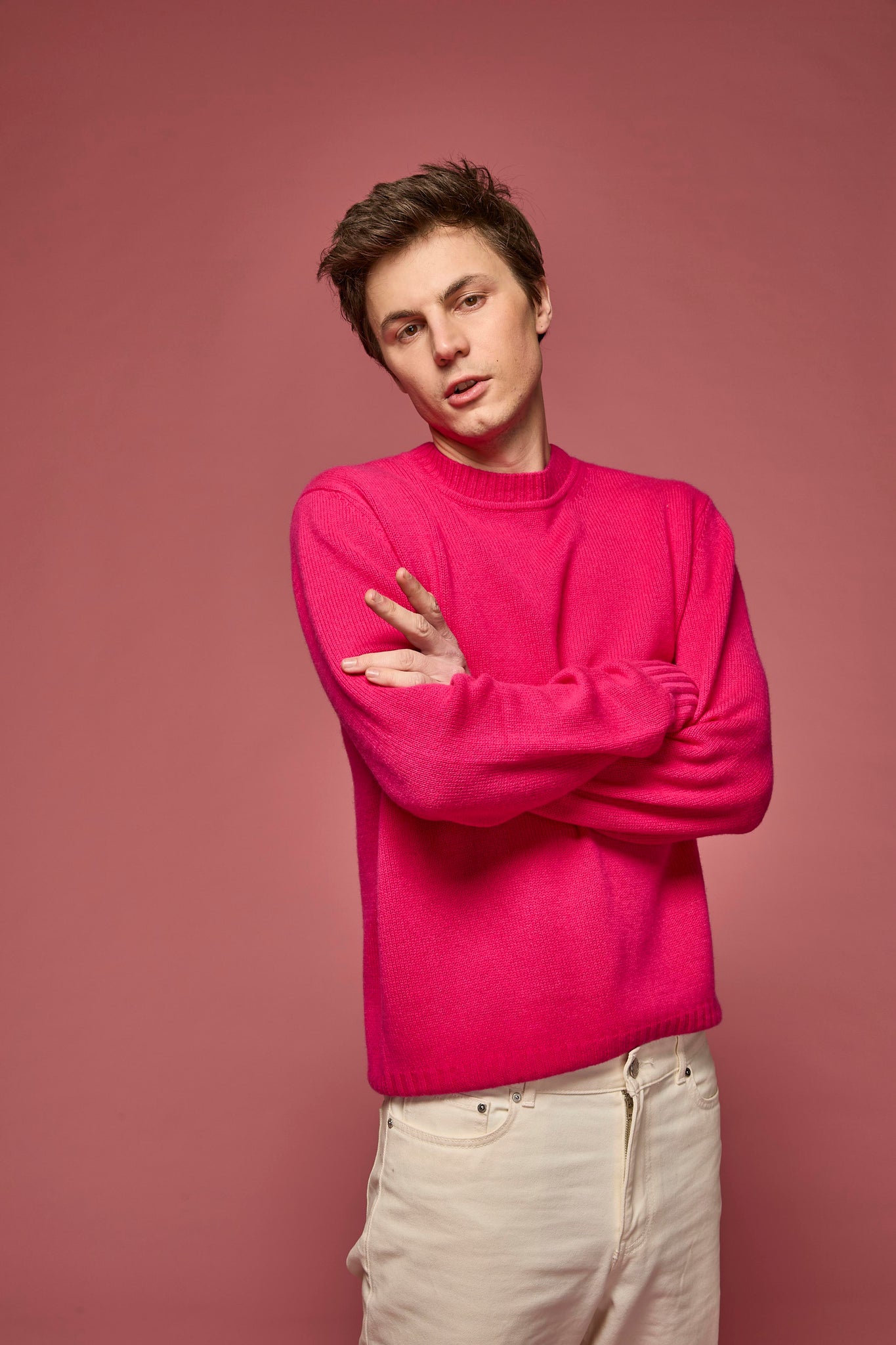 Man wearing a hot pink cashmere sweater against a pink background