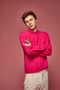 Man wearing a hot pink cashmere sweater against a pink background
